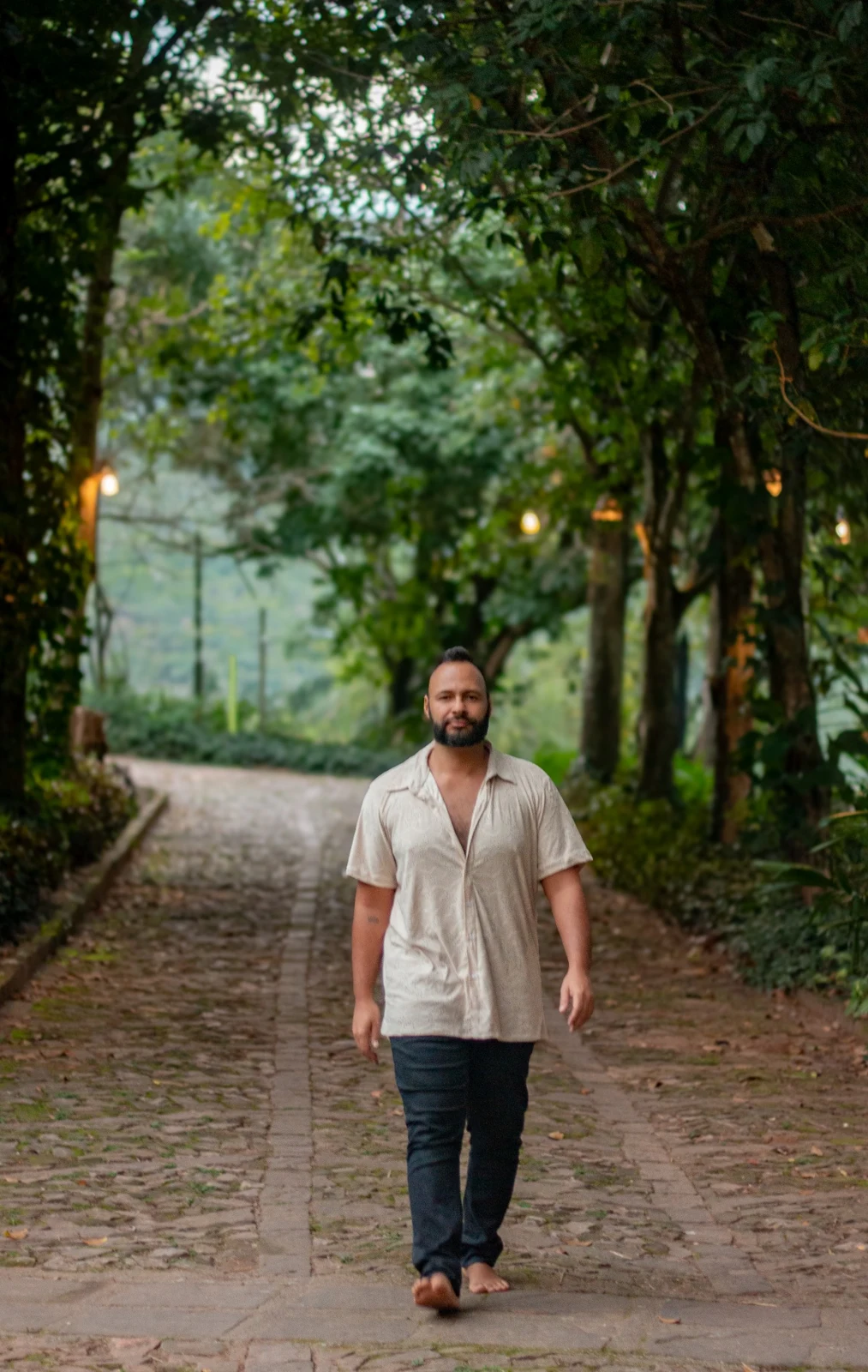 Gabriel caminhando descalço em um caminho cercado de árvores