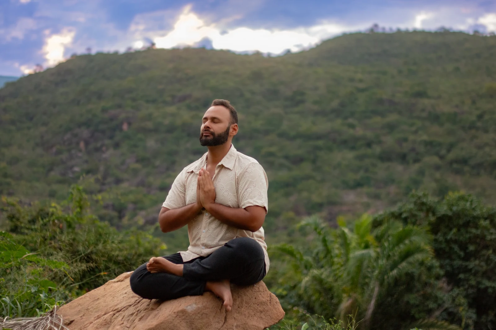 Gabriel Sabiá em meditação, sentado sobre uma rocha diante das montanhas